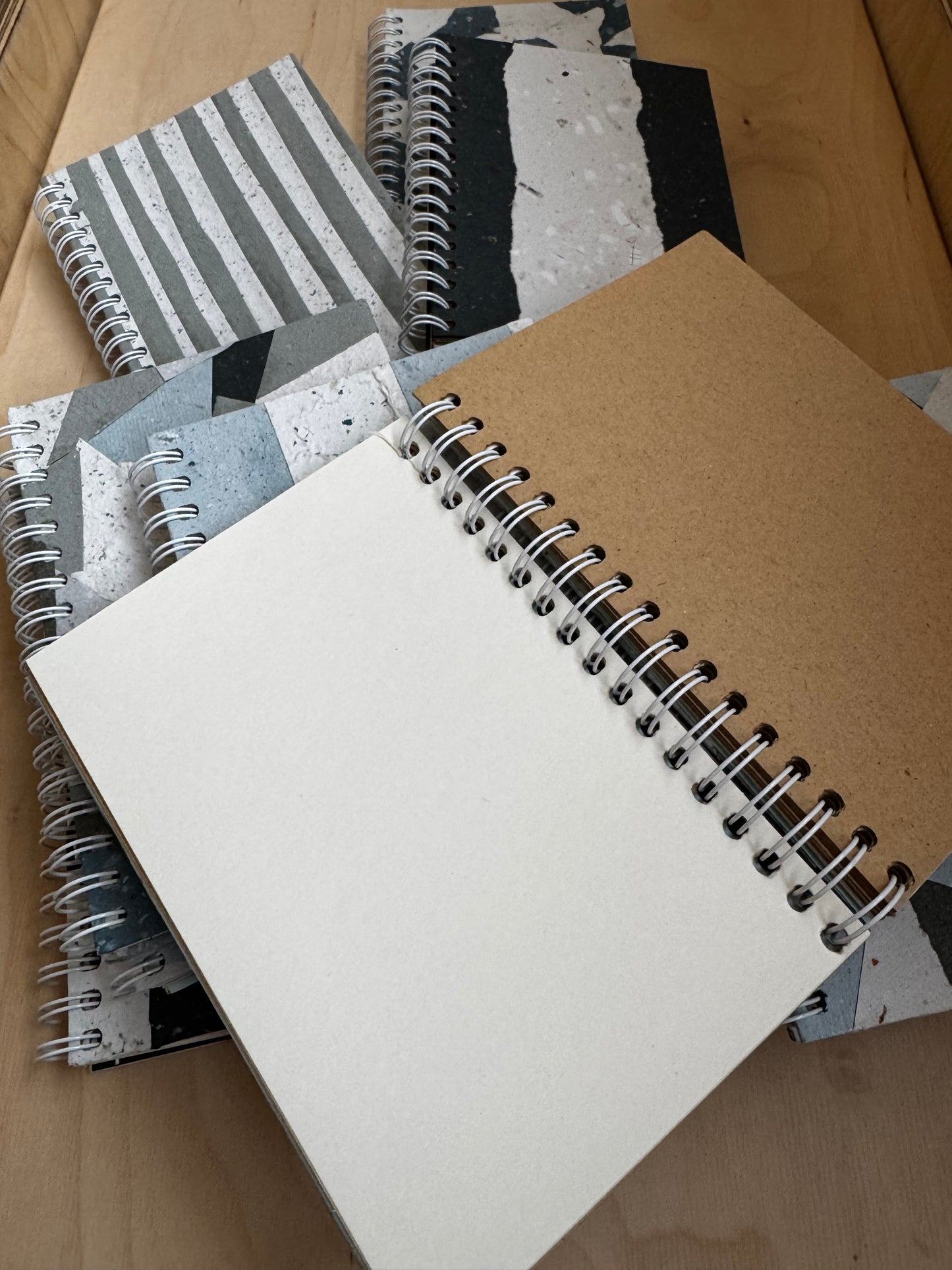 Stack of eco-conscious spiral notebooks with blank pages shows pristine inside covers.