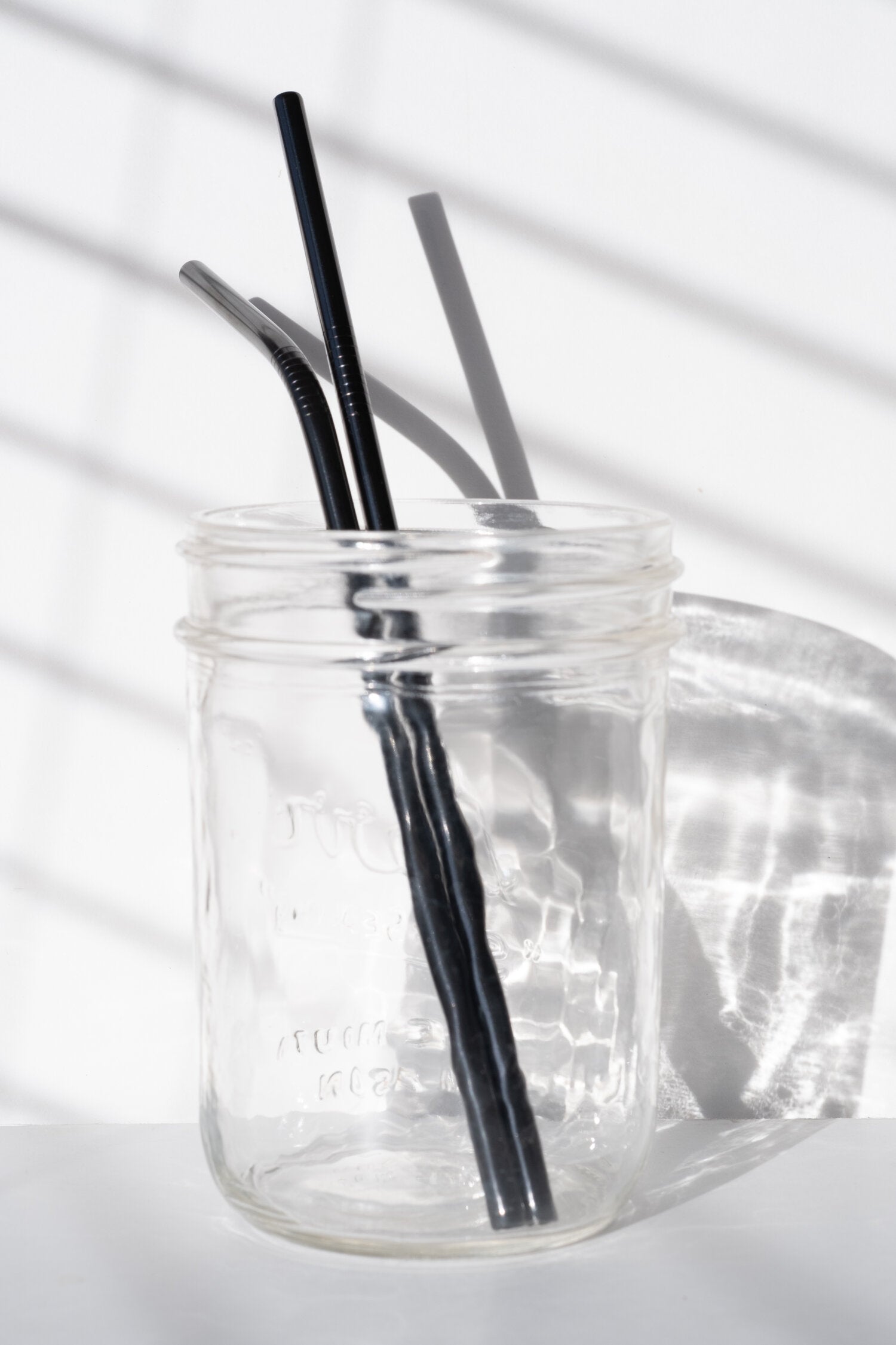 Two black stainless steel eco-friendly straws in a drink jar.
