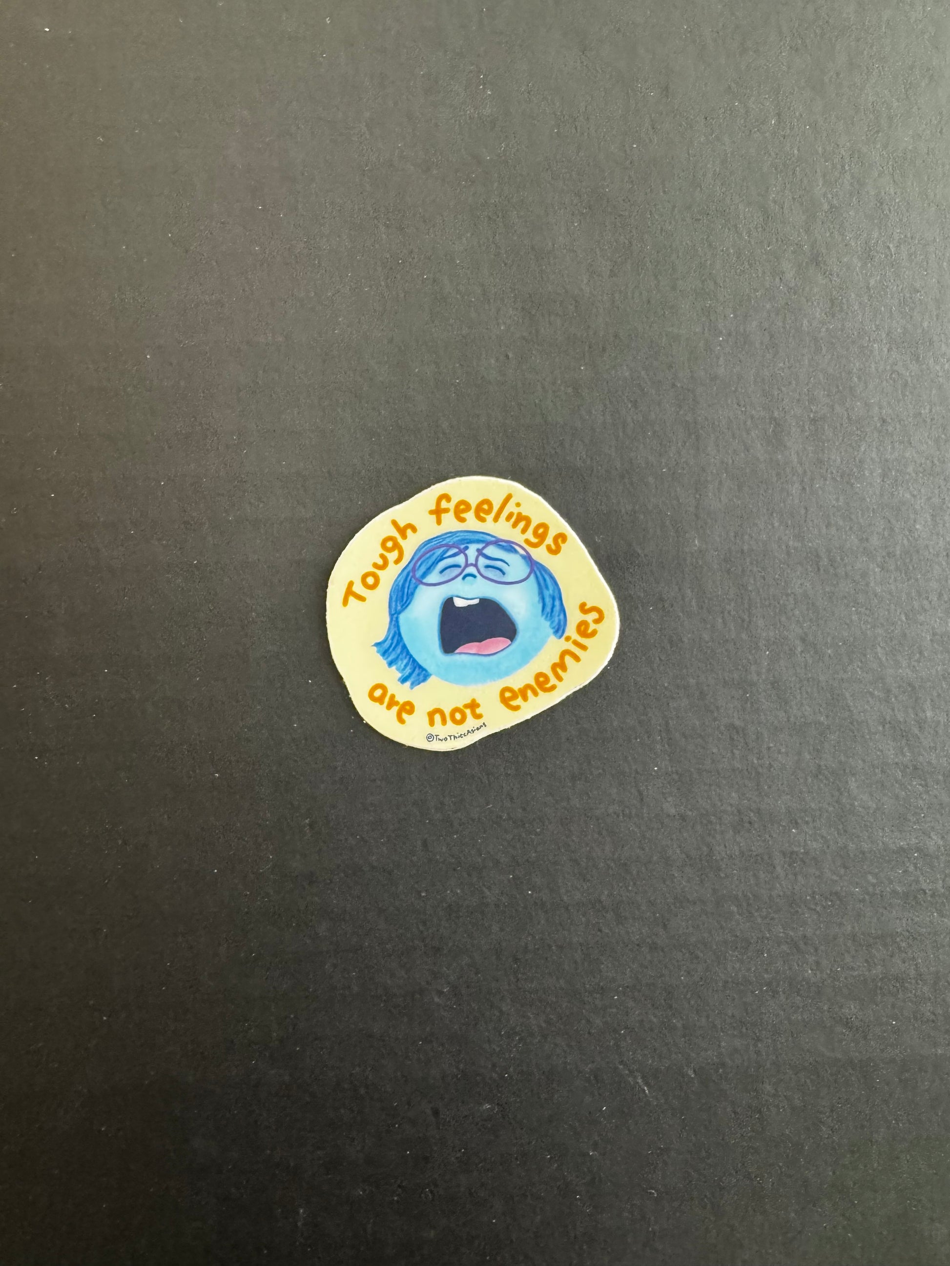 The feelings sticker shows the character Sadness bawling on a yellow background with orange text that says "Tough feelings are not enemies".